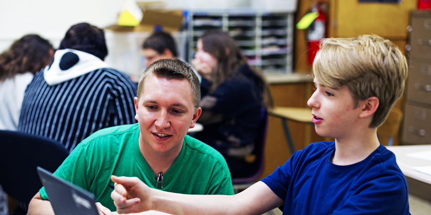 Teacher and student reviewing work together on a laptop.